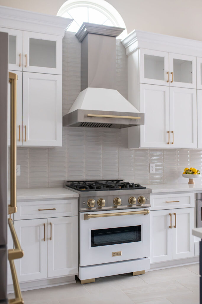 Gas stovetop and range in the kitchen with grey tile backsplash and stainless steel hood. Peninsula Ohio interior design Lindsey Putzier
