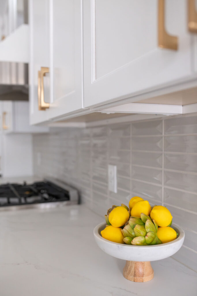Grey tile backsplash and light kitchen countertops and a fruit bowl. Peninsula Ohio Interior Design Lindsey Putzier