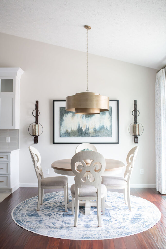 After of dining room table with new gold light fixture, wall sconces, and large artwork. Lindsey Putzier interior design Peninsula Ohio 