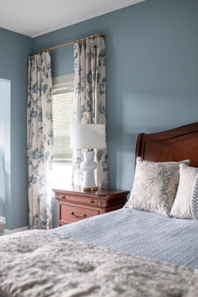 After of the master bedroom with blue colored walls and floral drapes. Lindsey Putzier interior design Peninsula Ohio