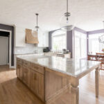 Kitchen remodel with large island, stone countertops, and pendant lighting. Aurora Ohio interior design Lindsey Putzier