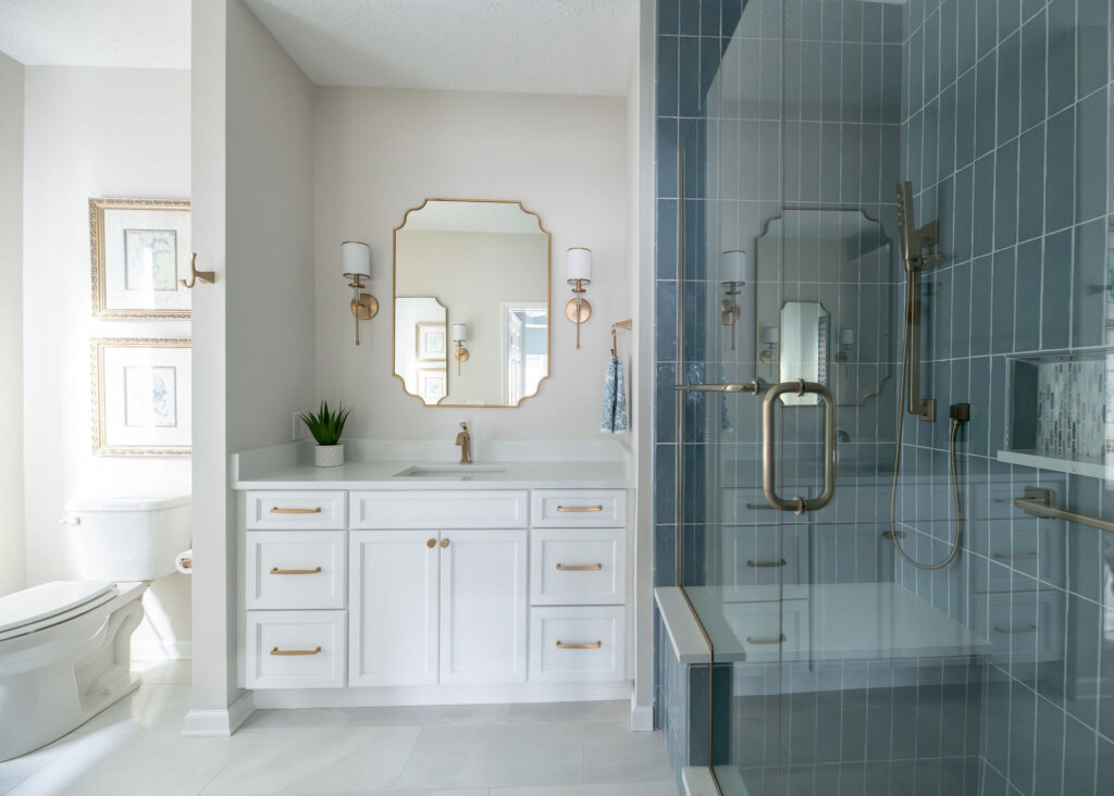 Master bathroom in Peninsula Ohio home with blue tiled shower, white vanity and golden hardware. Lindsey Putzier interior design
