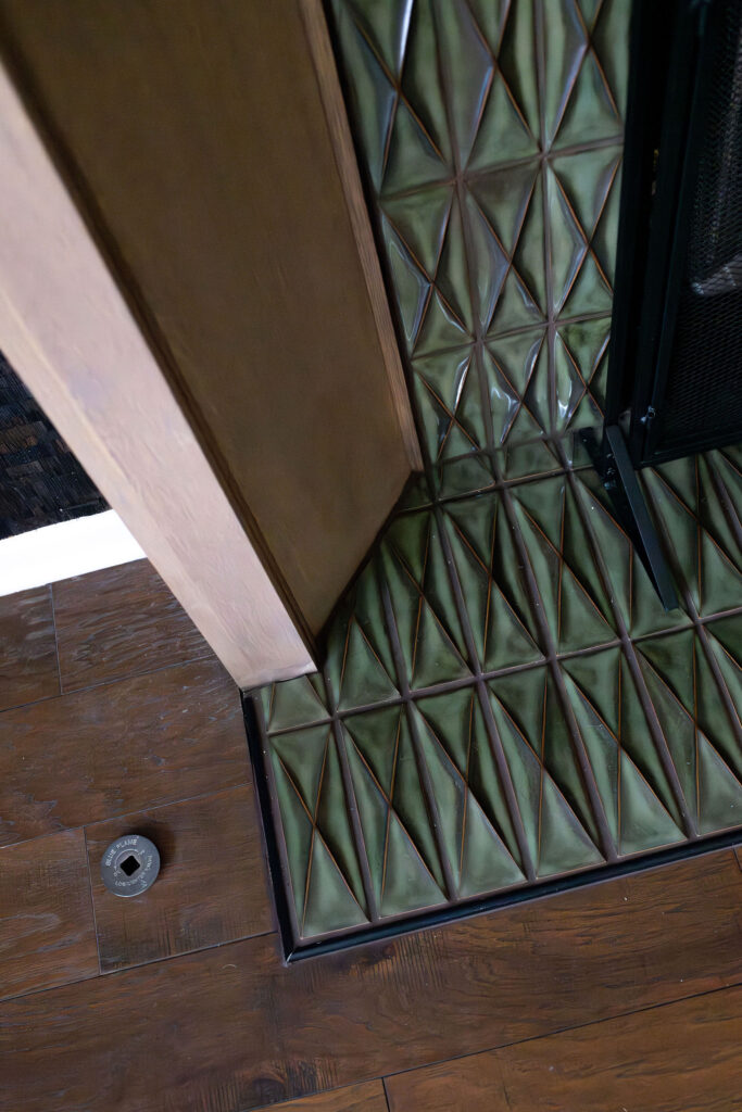 Updated tile on fireplace in the living room with green textured tile and wooden mantle. Lindsey Putzier interior design Copley Ohio 