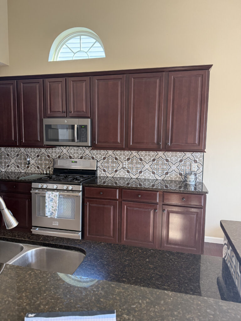 Before of Kitchen in Peninsula Ohio with dark cabinetry, patterend backsplash and dark countertops. Lindsey Putzier Interior design 