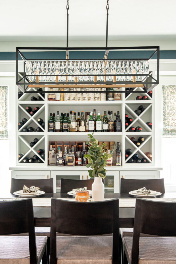 In home bar in the dining room with dark wooden table and light white custom shelving. Lindsey Putzier interior design 