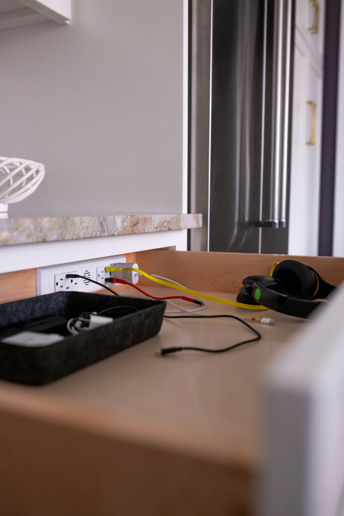 Integrated charging station in the kitchen drawer to charge devices and keep clutter off the counters. Lindsey Putzier interior design