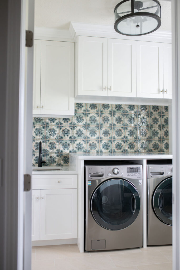 Laundry integrated into the mudroom with white cabinetry and patterned backsplash. Lindsey Putzier interior design