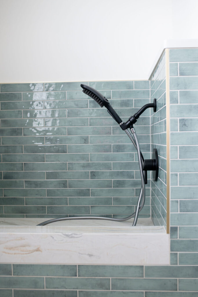 Mudroom with custom dog washing station with light blue tile, golden trim, and marble flooring. Lindsey Putzier interior design