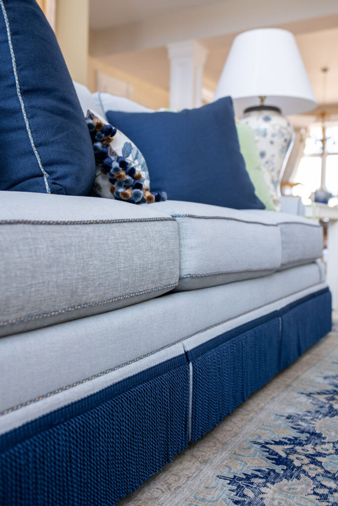 Sofa in the living room made with performance fabric, trimmed with deep blue fringe on the bottom and custom pillows on top. Lindsey Putzier interior design Aurora Ohio 