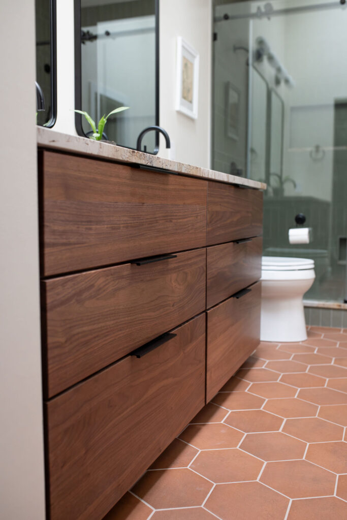 Vanity in the master bathroom with black fixtures, terracotta tiles flooring, and glass shower. Lindsey Putzier interior design Akron Ohio