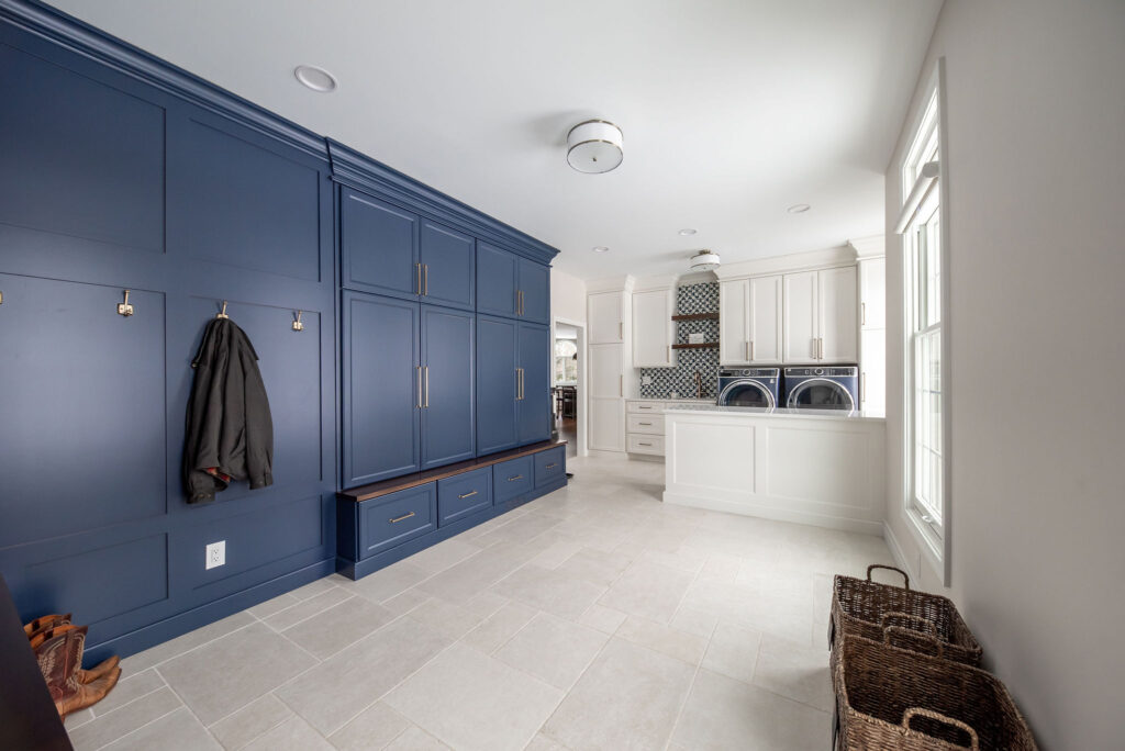 Mudroom with dark blue built in cabinets, tile flooring and laundry machines. Lindsey Putzier interior design