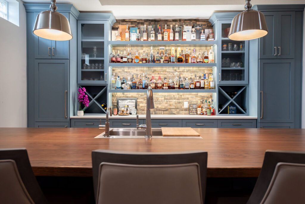 Basement bar with large island for entertaining, built in custom shelving for displaying bottles. Lindsey Putzier interior design  