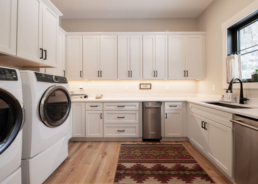 Mudroom with warm wooden flooring, wooven rug, and white custom cabinets. Lindsey Putzier interior design