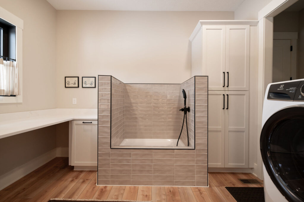 Custom built dog washing station in the mudroom with durable light tiles, and adjustable nossel. Lindsey Putzier Interior Design