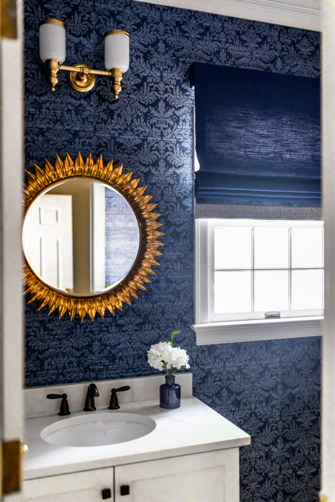 Circular mirror in the powder room with golden sunbeam accent. Lindsey Putzier interior design Hudson Ohio 