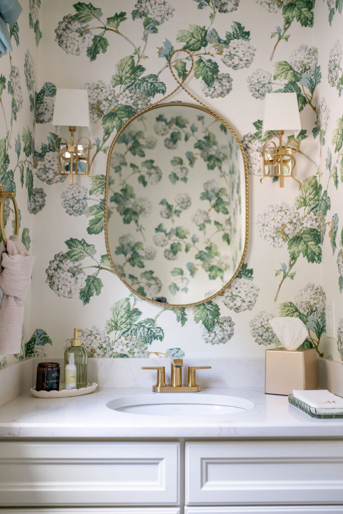 Powder room with floral wallpaper in green tones and light countertops and cabinetry. Lindsey Putzier interior design Hudson Ohio  