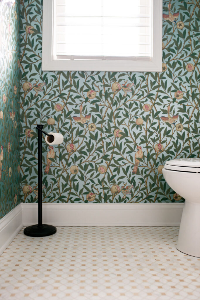 Powder room with wallpaper and black toilet paper holder 