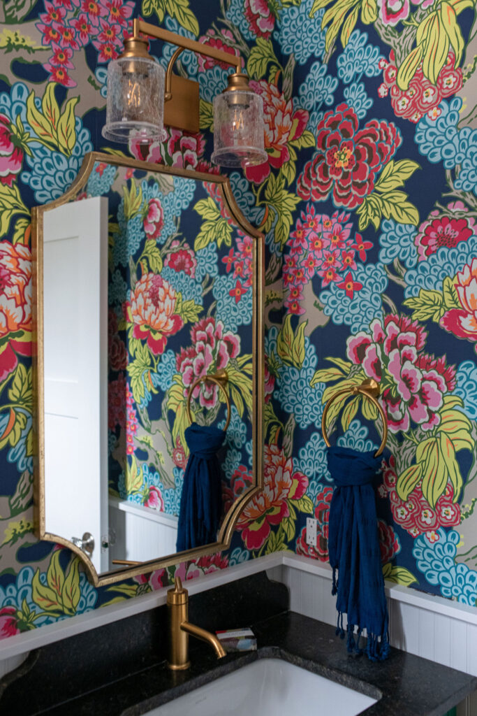 Powder room with colorful wallpaper and golden faucet, mirror and towel hook. Lindsey Putzier interior design Hudson Ohio 