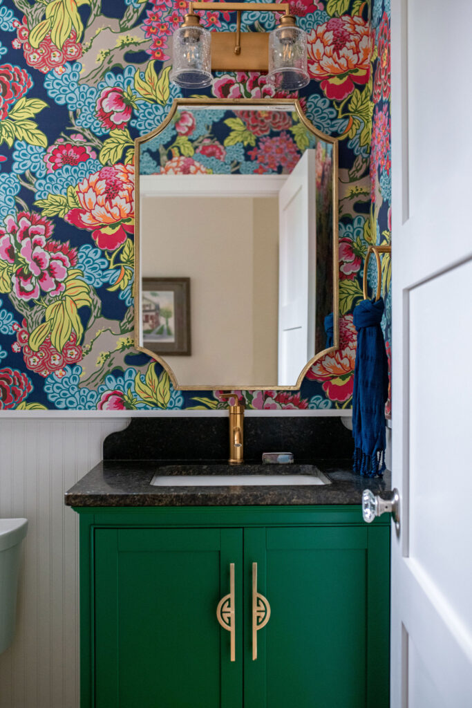 Powder room with colorful floral wallpaper and a deep green vanity. Lindsey Putzier interior design Hudson Ohio 