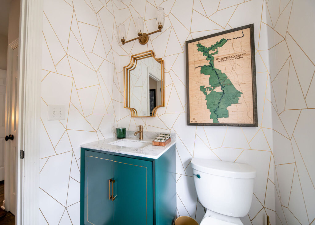 Powder room with teal vanity and asymmetrical wallpaper. Lindsey Putzier interior design Hudson Ohio 