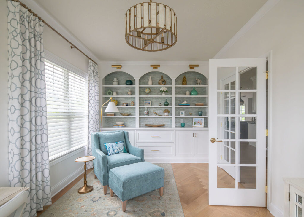 Home office design with a whole wall of styled shelving and a reading chair. Hudson Ohio interior design Lindsey Putzier 