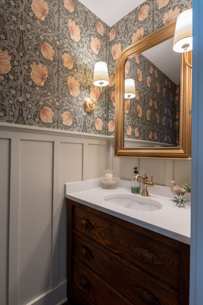 Powder room with wallpaper on the top 3/4 of the wall, wooden vanity and polished accents. Lindsey Putzier interior design Hudson Ohio 