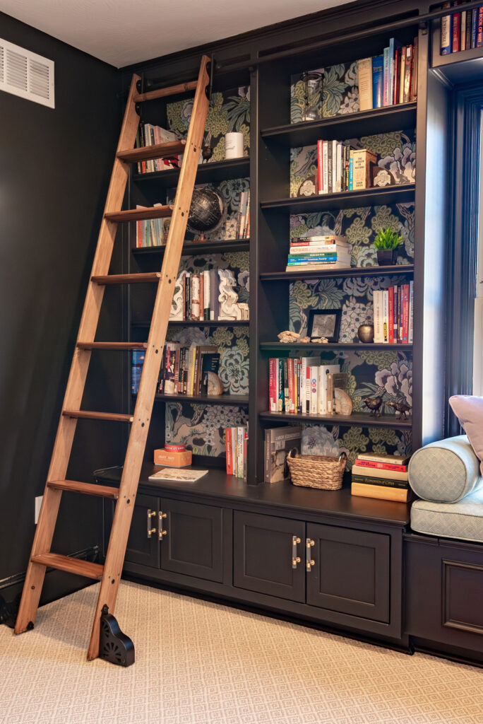 Bookshelves displaying books and other design elements with a built in sliding ladder. Lindsey Putzier interior design Hudson Ohio 