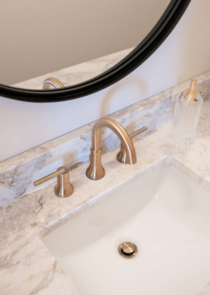 Golden faucet and marble countertops in the powder room. Lindsey Putzier interior design Hudson Ohio 