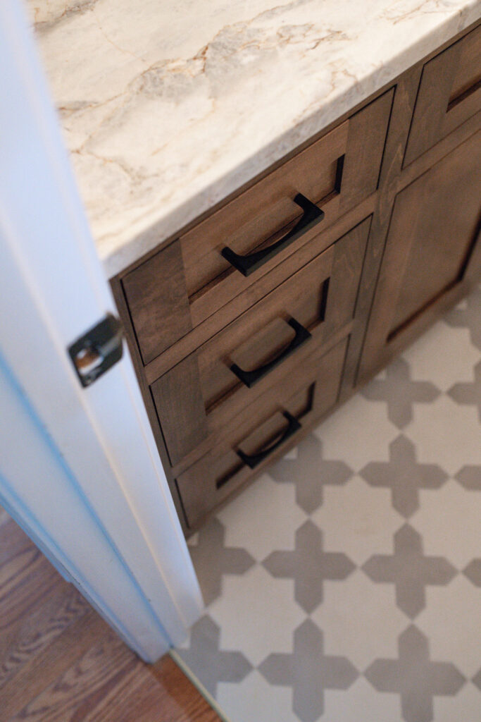 Powder room in Hudson Ohio house with patterned flooring and wooden vanity. Lindsey Putzier interior design 