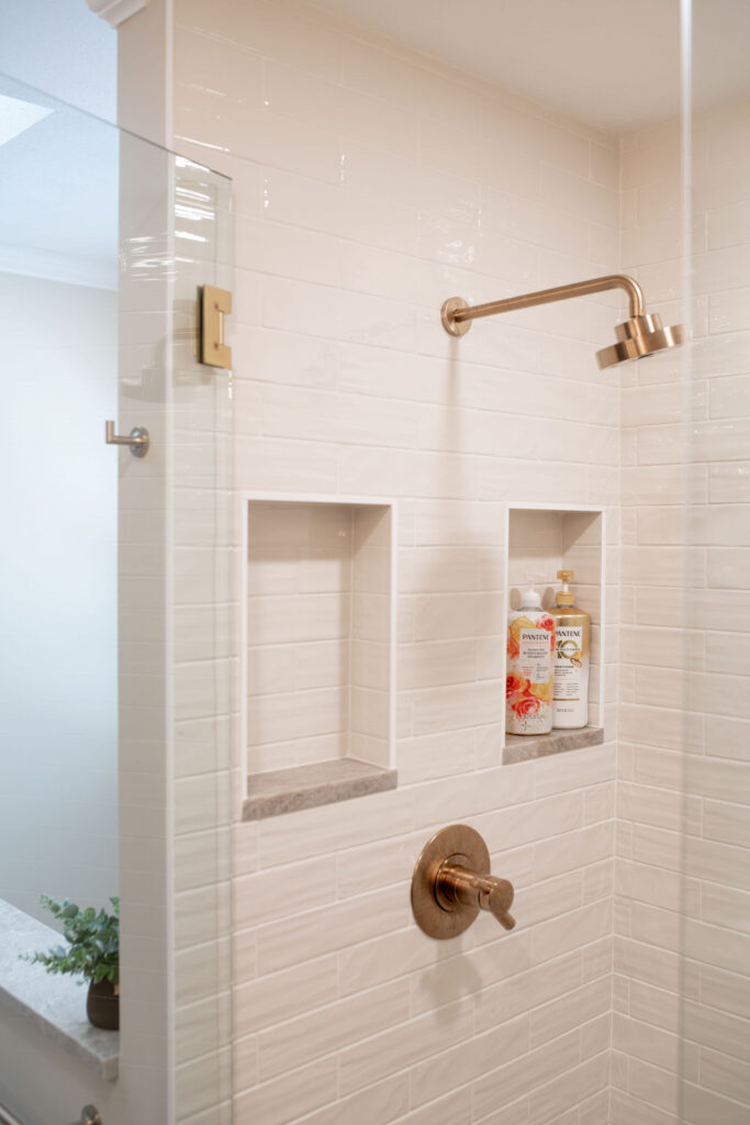 Master bathroom in Hudson Ohio with neutral tile shower and golden faucet. Lindsey Putzier interior design 