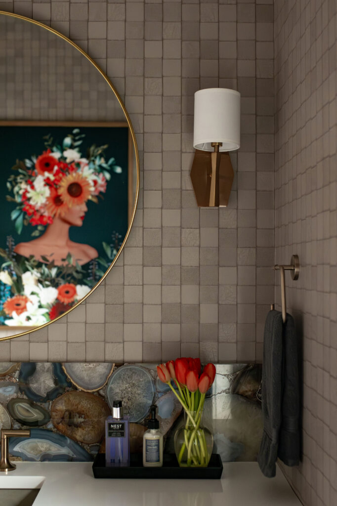 Golden Circular mirror in the powder room with colorful floral painting and rock backsplash. Lindsey Putzier interior design Hudson Ohio 