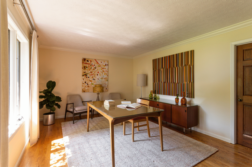 Home office with large open free standing wooden desk, and colorful art. Hudson Ohio interior design Lindsey Putzier 