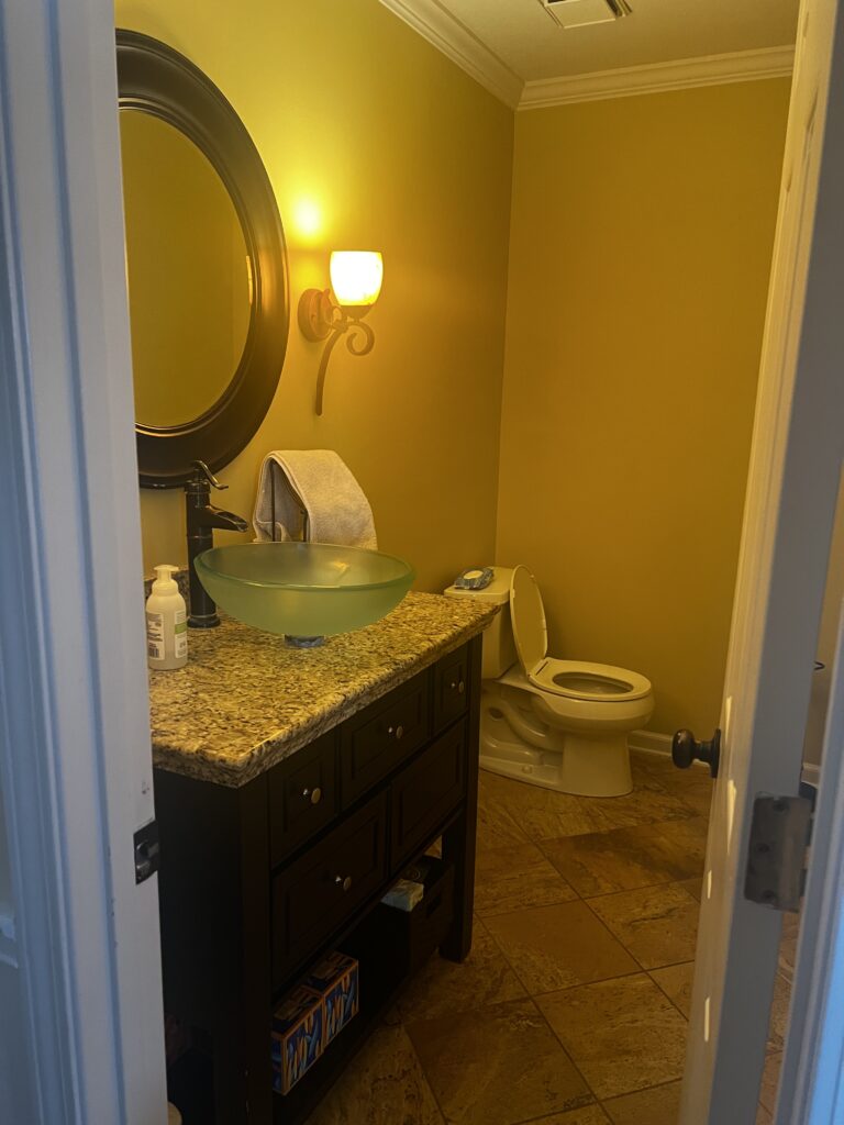 Before of the powder room with dark wooden vanity and mirror. Lindsey Putzier interior design.