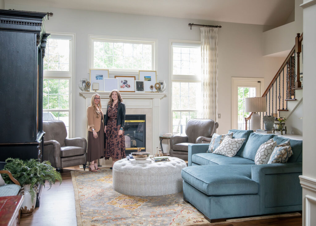 Lindsey Putzier, founder and principal designer, and Julianna Watts, Senior designer, standing in updated living room of Aurora Ohio home. Interior design.  
