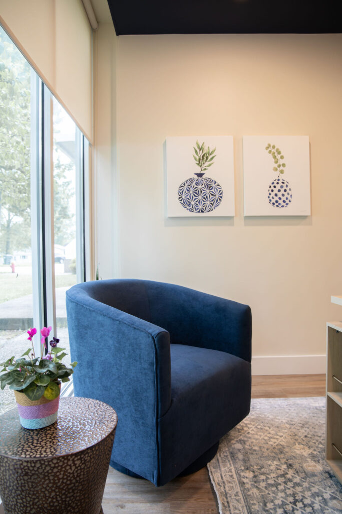 Blue chair in the executive office with brass table. Cuyahoga Falls Ohio. Lindsey Putzier interior design