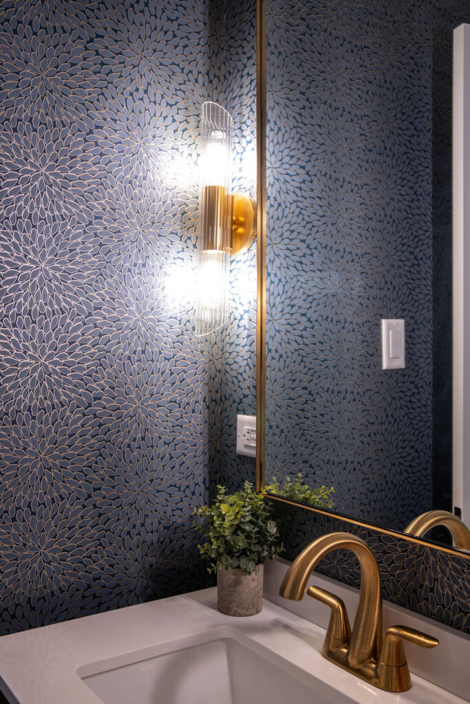 Bathroom with blue wallpaper, gold lighting and fixtures, and new vanity. Cuyahoga Falls Ohio. Lindsey Putzier interior design