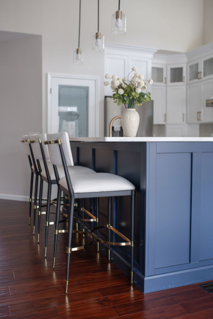 Kitchen with dark blue island, pendant lighting and upholstered chairs. Lindsey Putzier interior design Hudson Ohio