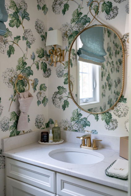 golden mirror hanging in the powder room above the sink. Lindsey Putzier interior design Hudson Ohio