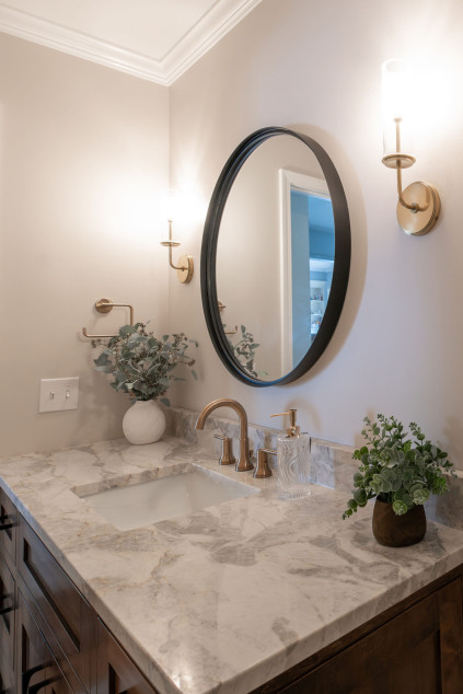 Circular mirror in the bathroom hung above the sink. Lindsey Putzier interior design Hudson Ohio