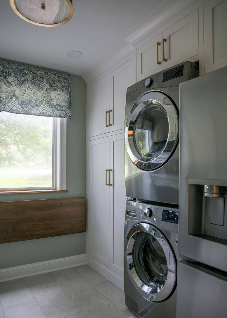 Stacked washer and dryer in the mudroom with cabinetry for storage and fridge. Hudson Ohio interior design Lindsey Putzier