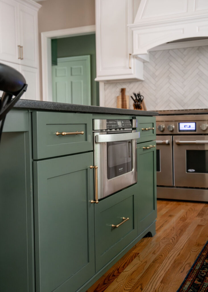 Newly painted green island with a microwave and golden handles. Lindsey Putzier interior design Hudson Ohio  