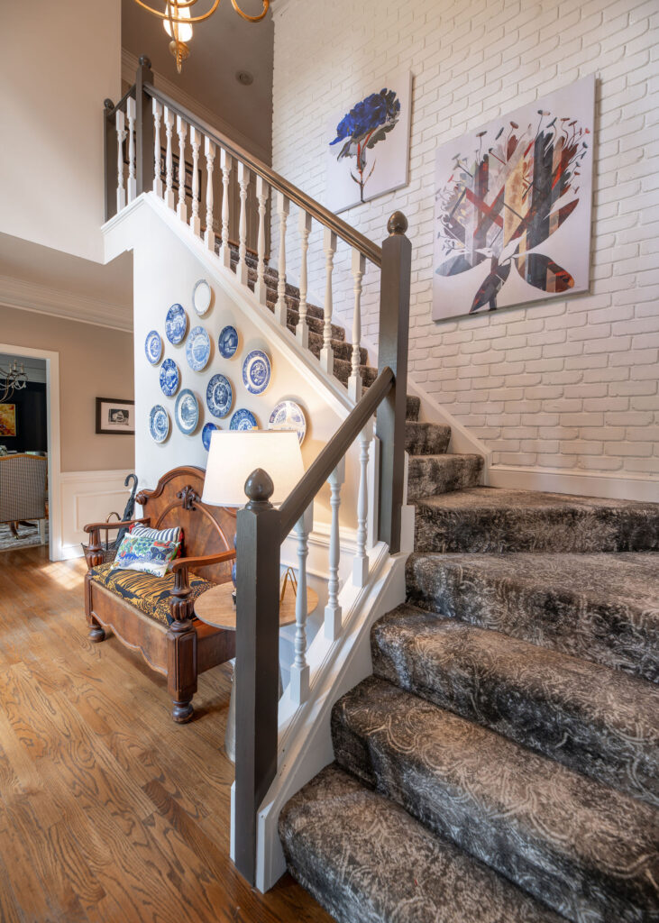 After of the front hallway with updated carpet on the stairs, new wall decor and a new bench. Hudson Ohio Interior design Lindsey Putzier